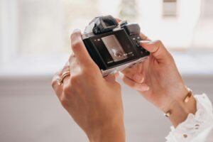 Detailed view of hands holding a camera indoors, showcasing a digital display.